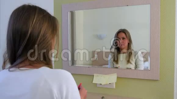女青年在酒店房间照镜子时化妆视频的预览图