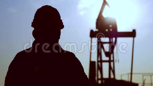 油钻现场泵千斤顶轮廓与夕阳和工人油田油工在干活视频的预览图
