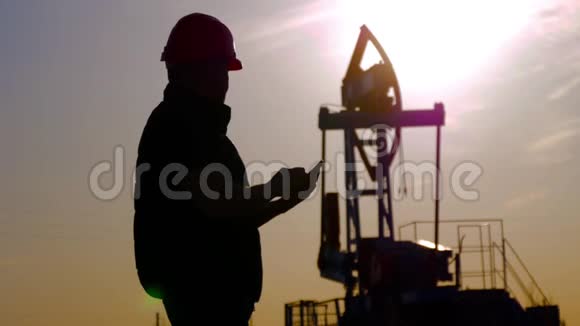 油钻现场泵千斤顶轮廓与夕阳和工人油田油工在干活视频的预览图