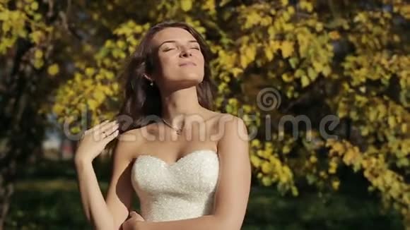 穿着白色裙子的新娘秋天公园正对着镜头视频的预览图