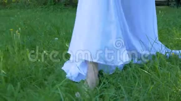 一个穿着白色连衣裙的年轻女子赤脚走在草地上夏日视频的预览图