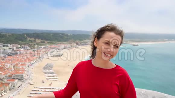 葡萄牙拿撒勒市上方的一座小山上穿着红裙子的女人在上面放松视频的预览图