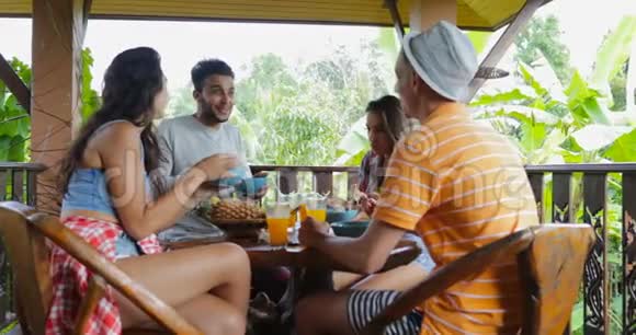 人们吃面条交谈朋友组坐在露台上观看热带森林视频的预览图