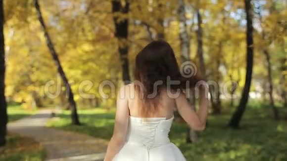 美丽的黑发新娘在秋天公园散步视频的预览图