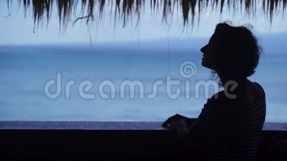 一个女孩的剪影她看着远处的蓝色海洋年轻女子欣赏这热带度假胜地视频的预览图