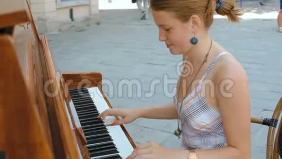 穿着连衣裙的年轻姑娘正在街上弹着夏天的钢琴视频的预览图