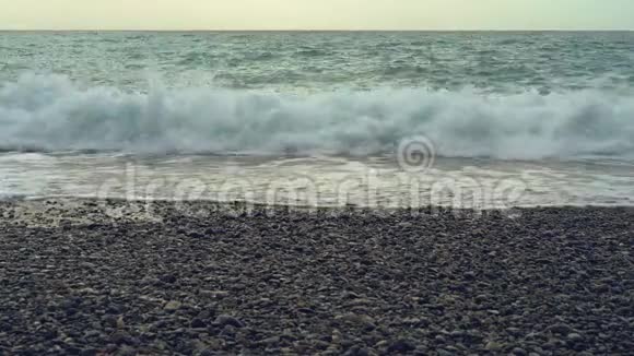 波浪冲刷卵石滩波浪再次拍打着一片光滑的海滩用白色的泡沫覆盖它波浪撞击视频的预览图
