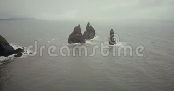 冰岛水中巨魔脚趾山的鸟瞰图雾天直升机在海中绕着悬崖飞行视频的预览图