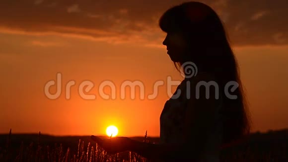 女孩手里拿着夕阳女孩的剪影在夕阳的背景下视频的预览图