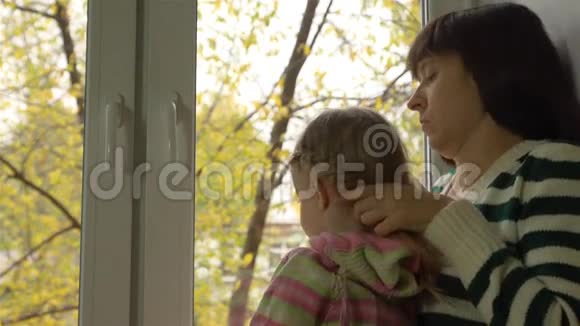 在一个阴天的秋日母亲在窗台上编织女儿的头发视频的预览图