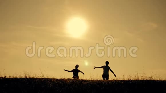 两个男孩在日落时玩一架木飞机孩子们玩飞机的剪影飞行的梦想儿童视频的预览图