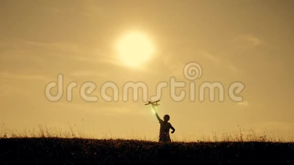 两个男孩在日落时玩一架木飞机孩子们玩飞机的剪影飞行的梦想儿童视频的预览图