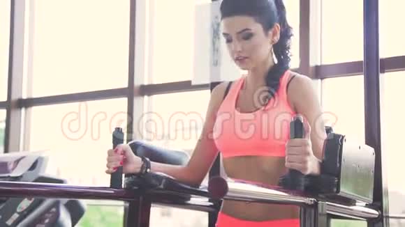 在健身房的模拟器里一个可爱的黑发年轻女人在锻炼腿部肌肉视频的预览图