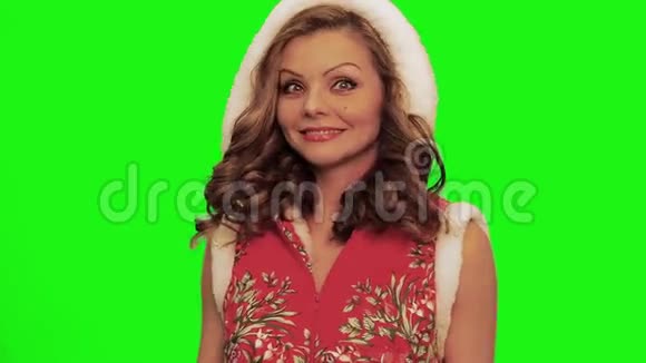 漂亮的女人穿着圣诞服装调整头发使脸和微笑对抗色度视频的预览图