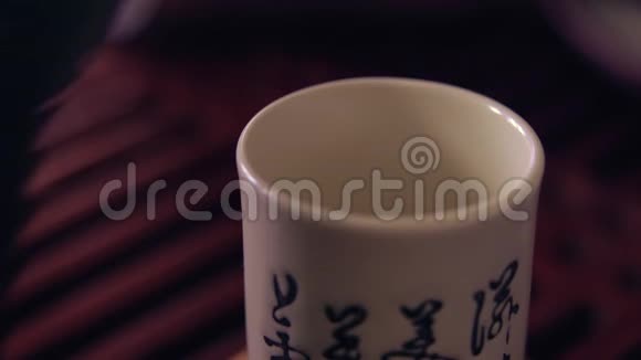 中国传统茶道的动作在一个杯子里把茶从茶壶里倒出来木制茶板视频的预览图
