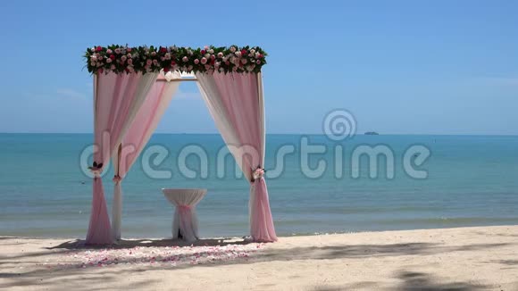 海边沙滩上的粉色婚礼拱门视频的预览图