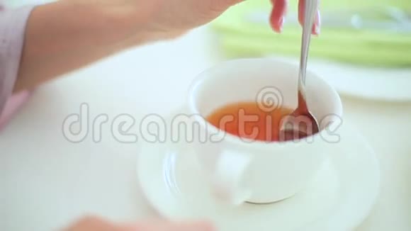 女人把茶和勺子混合在一起视频的预览图