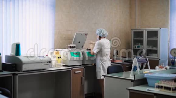 诊所的医生穿着一件白色的外套在实验室里把血液测试放在一个离心机里视频的预览图