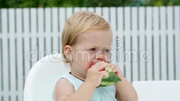夏天在花园里有趣的一岁金发女孩吃西瓜视频的预览图