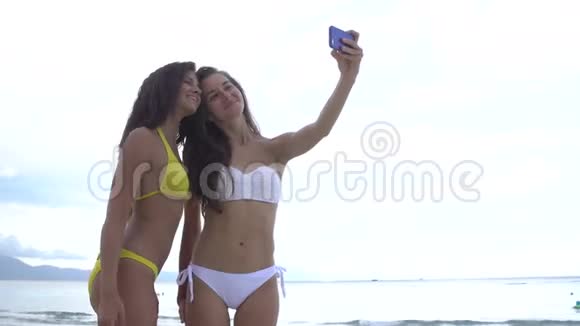 美丽的女孩在海滩上用手机自拍微笑着享受假期视频的预览图