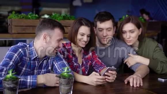 两对在一起愉快的朋友在一部手机上拍照留念视频的预览图