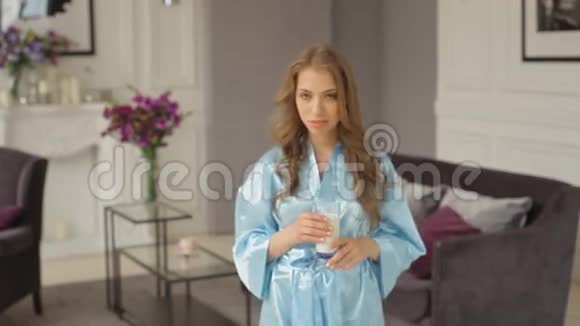 穿着蓝色长袍的年轻女士走近前来喝牛奶视频的预览图