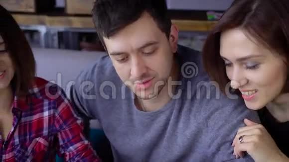 一位留着黑色短发的成年男子穿着一件羊绒衫和他的女友朋友坐在餐馆里视频的预览图