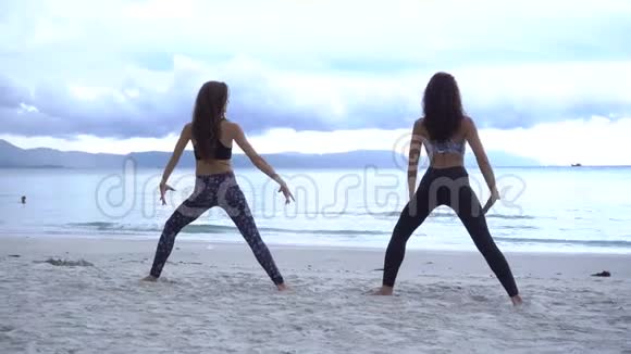 年轻女性穿着运动服在海滩上做瑜伽视频的预览图