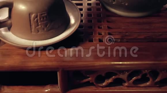 用泥杯和茶壶在沙班上倾斜拍摄茶几上的中国传统茶道视频的预览图
