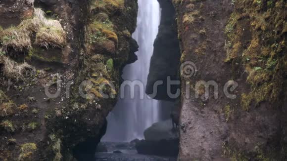 美丽的风景强大的瀑布在冰岛两座山之间游客们在探索这一景象视频的预览图