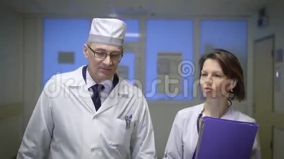 医院大厅两名医生两名穿着特别制服的高级医生在医院大厅散步视频的预览图