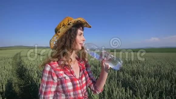 年轻女子在麦田里喝水降温视频的预览图