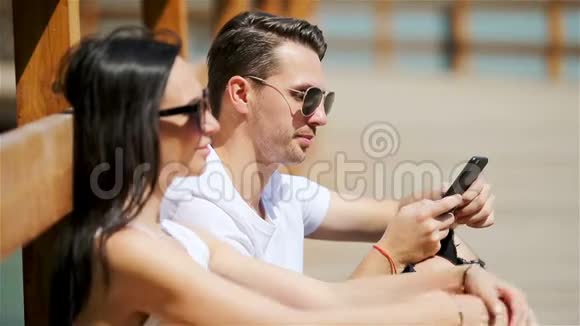 一对快乐的夫妇在公园里使用智能手机视频的预览图