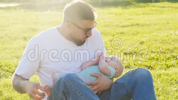 夏天傍晚日落时父子俩坐在草地上视频的预览图