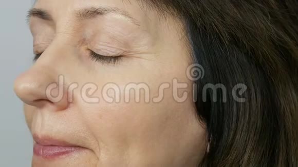 化妆师用高光遮瑕膏给蓝眼睛的中年妇女化妆年龄化妆特写肖像视频的预览图