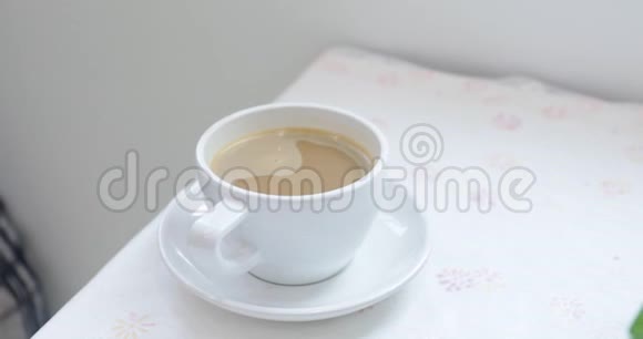 近距离观看女性手拿一个白色杯子与热咖啡从桌子上视频的预览图