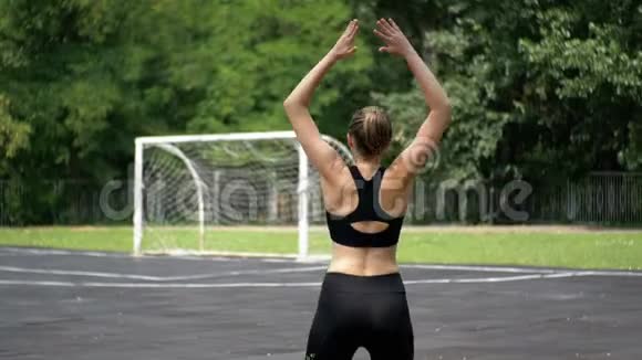 在公园的运动场上从事健身运动的年轻运动员女子的后景视频的预览图