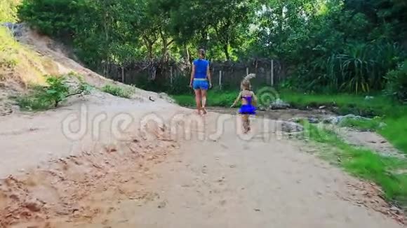 母亲的小女儿走在沙滩上浅溪视频的预览图