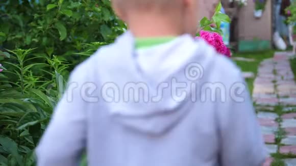 开花园花孩子沿着小路沿着花跑男孩在花园里玩耍视频的预览图