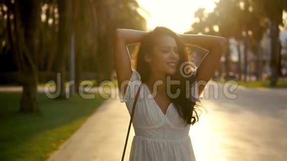 穿着白色裙子的女孩沿着棕榈树露台散步视频的预览图
