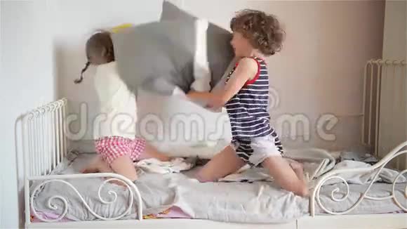 哥哥和姐姐在卧室的床上用枕头安排打架那个淘气的小女孩打败了视频的预览图