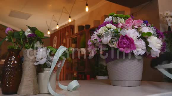 花店花店花店布置现代花束织带做蝴蝶结年轻英俊的花店花店工作视频的预览图