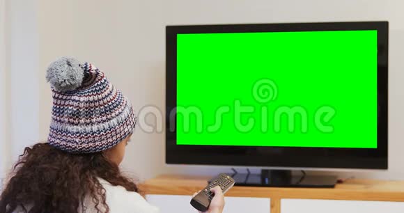 穿着温暖衣服看电视的微笑女人视频的预览图