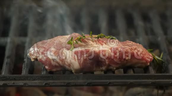 用香料腌制的牛排撒上橄榄油在烤架上烤出一串百里香和迷迭香视频的预览图