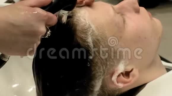 理发师在沙龙里给那个男头洗视频的预览图