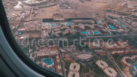 从埃及沙漠的热带度假胜地的飞机窗口可以看到异国情调的酒店和游泳池视频的预览图