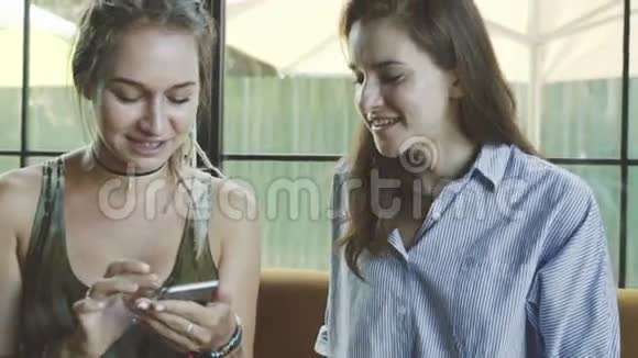 两个年轻的女朋友用智能手机在咖啡馆聊天视频的预览图