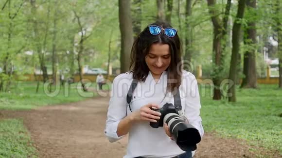 年轻女性摄影师在公园大自然户外拍摄视频的预览图