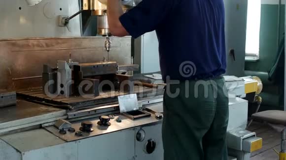 一个人专门在一台金属工件上的钻床上钻洞这是个小生意视频的预览图