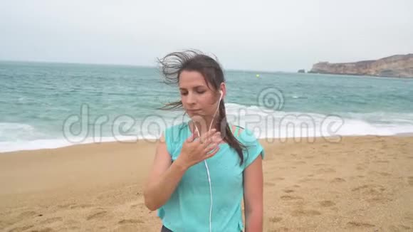 海滩上的女人用智能手机耳机听音乐葡萄牙拿撒勒视频的预览图